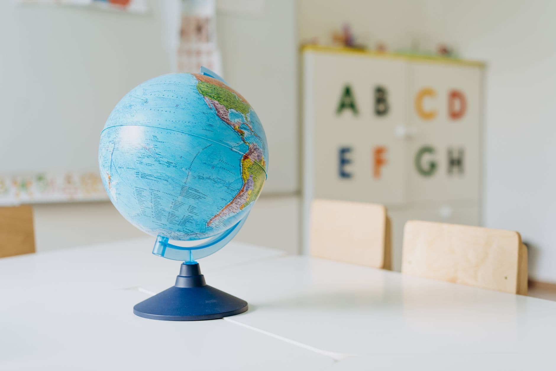 A vibrant globe sits on a table in a classroom, ideal for educational themes.